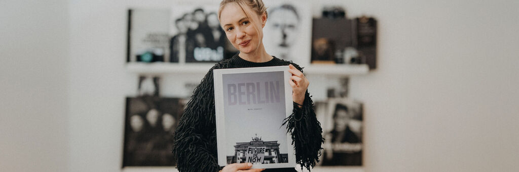 Marta Urbanelis steht vor ihrer Bücherwand und hält ein CEWE FOTOBUCH mit dem Titel "Berlin" in den Händen.