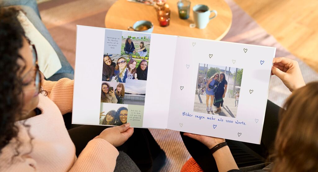 Eine person zeigt stolz ein offenes Fotobuch mit persönlichen Erinnerungen im Wohnzimmer.