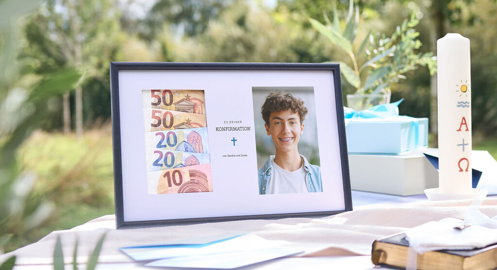 Gerahmtes Geschenk zur Konfirmation mit Euro-Geldscheinen und Foto, daneben Kerze und Geschenke