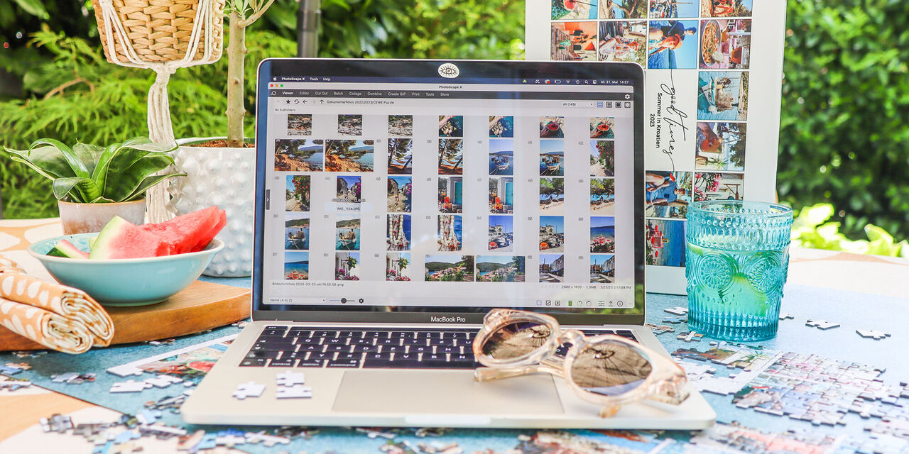 Laptop zeigt Urlaubsbilder auf dem Tisch mit Sommerflair