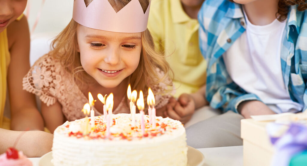 Kinder feiern mit Freude einen Geburtstag und blasen Kerzen aus