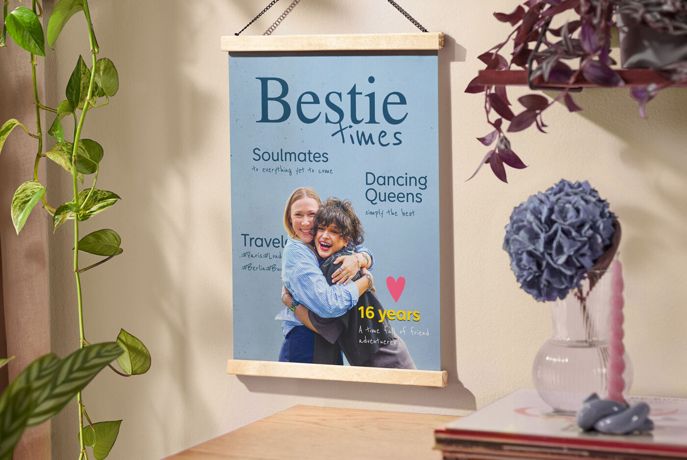 Hängendes Poster „Bestie times“ mit Umarmungsfoto, umgeben von Pflanzen.